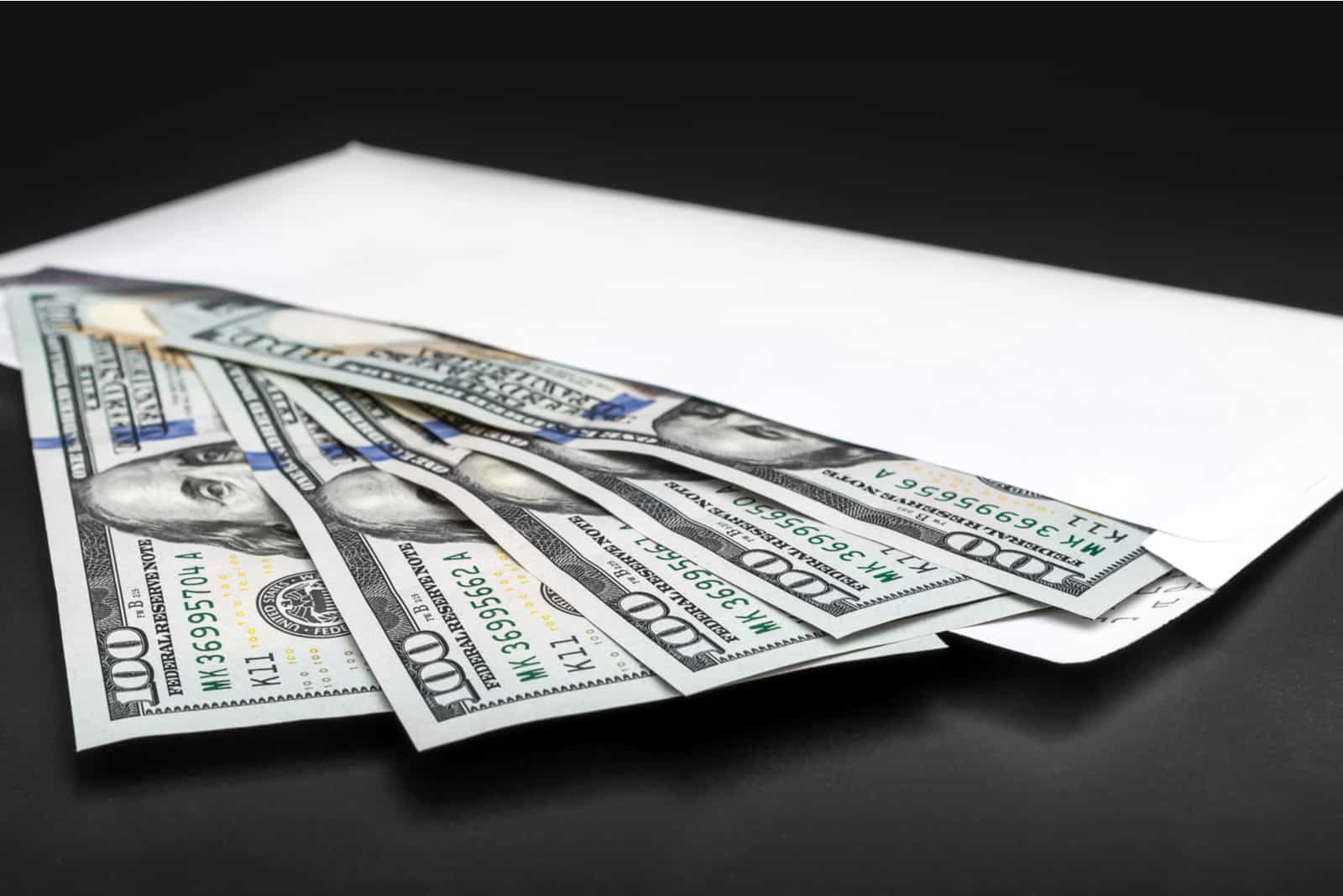 Umschlag mit Dollarnoten auf schwarzem Hintergrund
