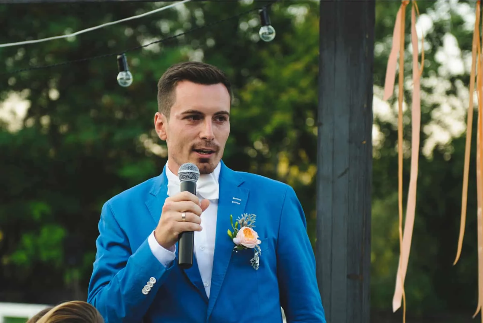 Bräutigam hält Mikrofon und spricht Sprache