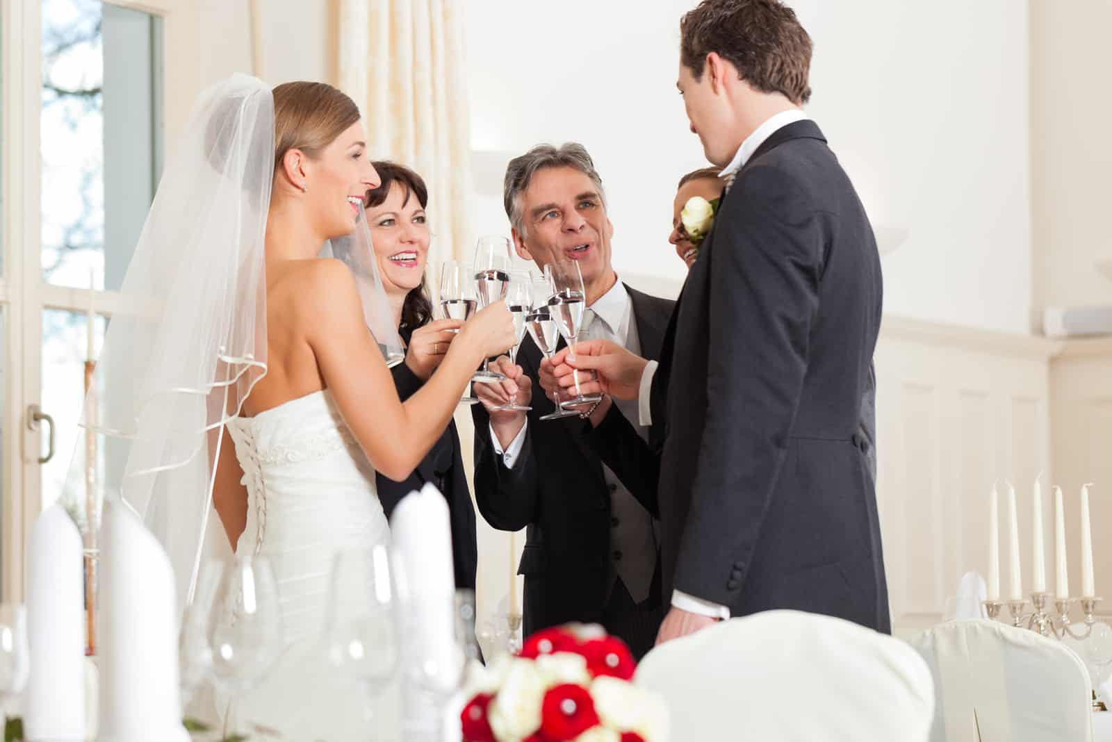 Bräutigam und Brautvater klirren Gläser mit Sekt