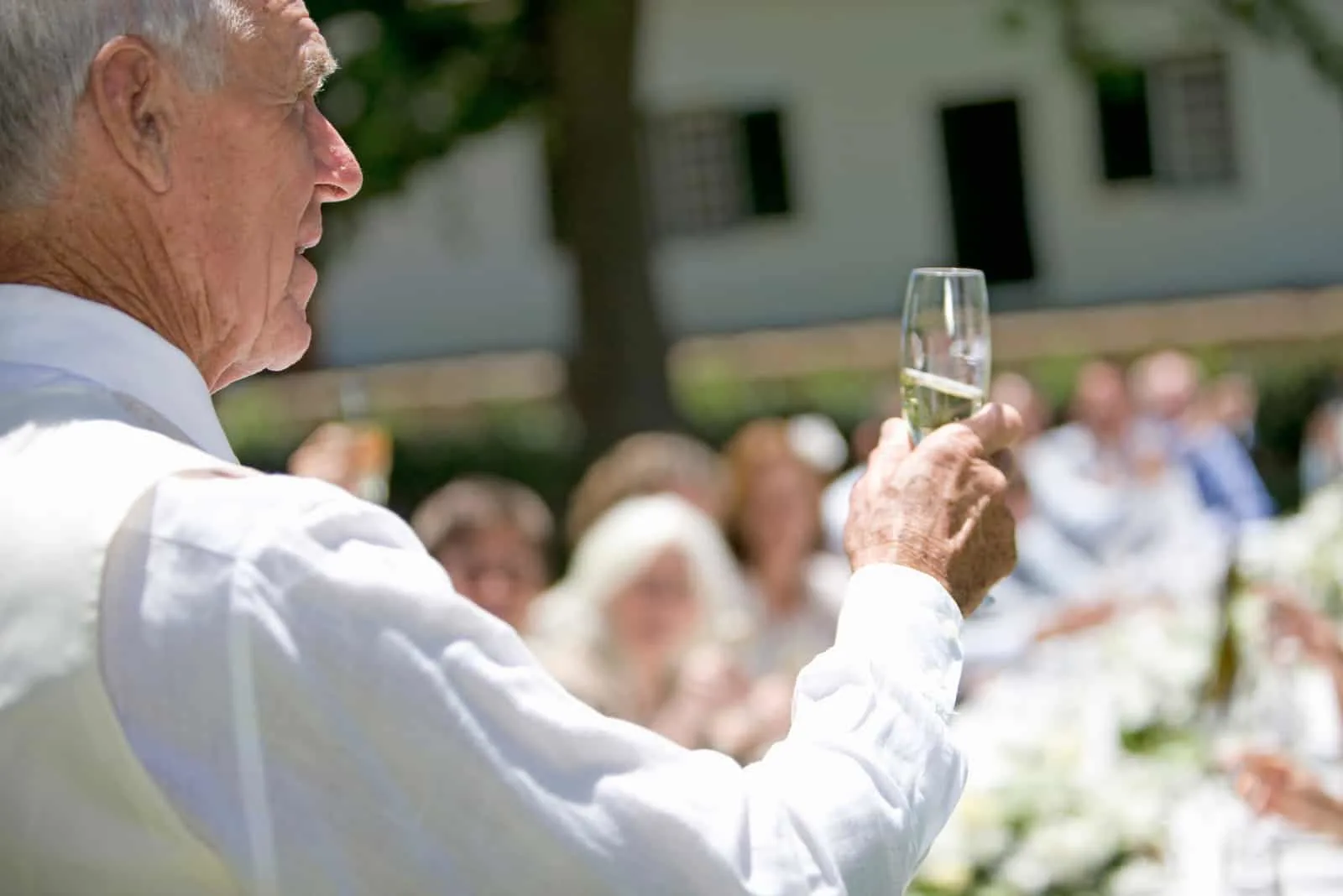 Ein älterer Mann, der ein Champagnerglas bei einer Hochzeit anhebt