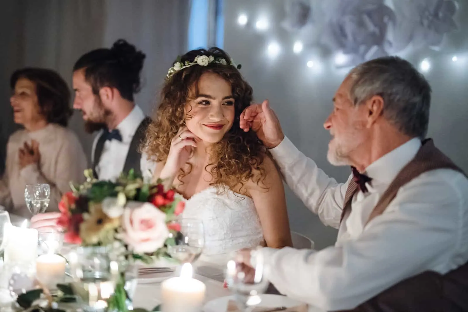 Ein liebender Vater und eine schöne Braut, die am Tisch auf einer Hochzeit sitzen und sprechen.