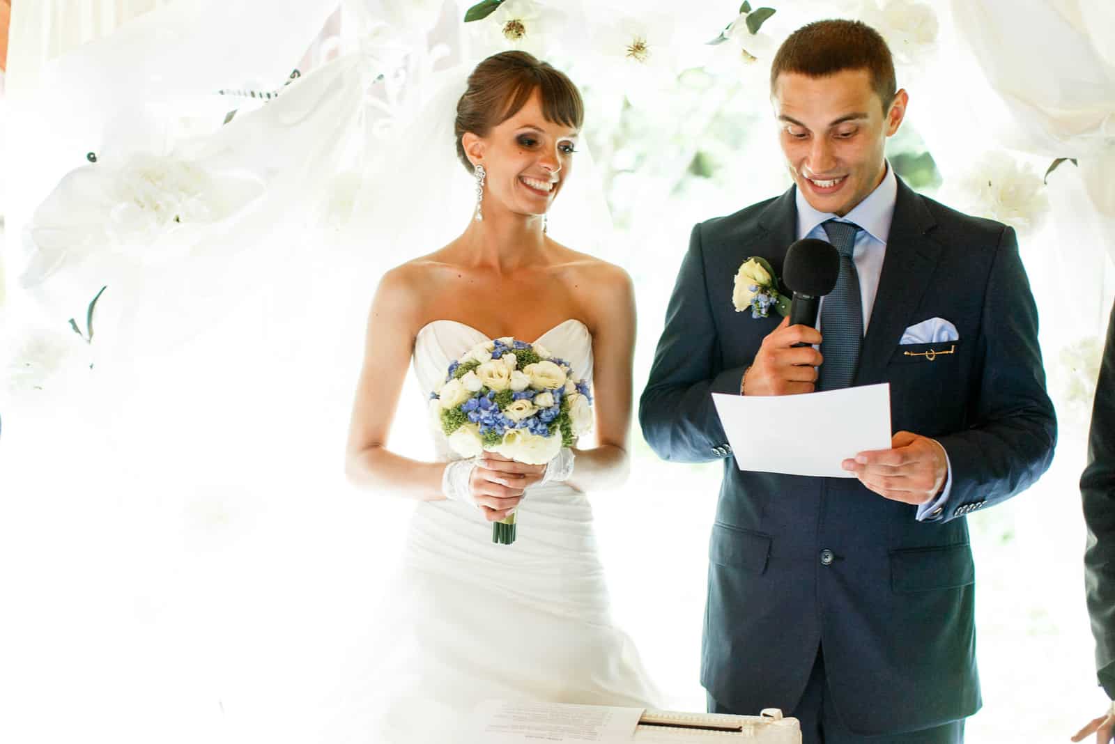 lächelnder Bräutigam und Braut auf den weißen Vorhängen des Hintergrunds