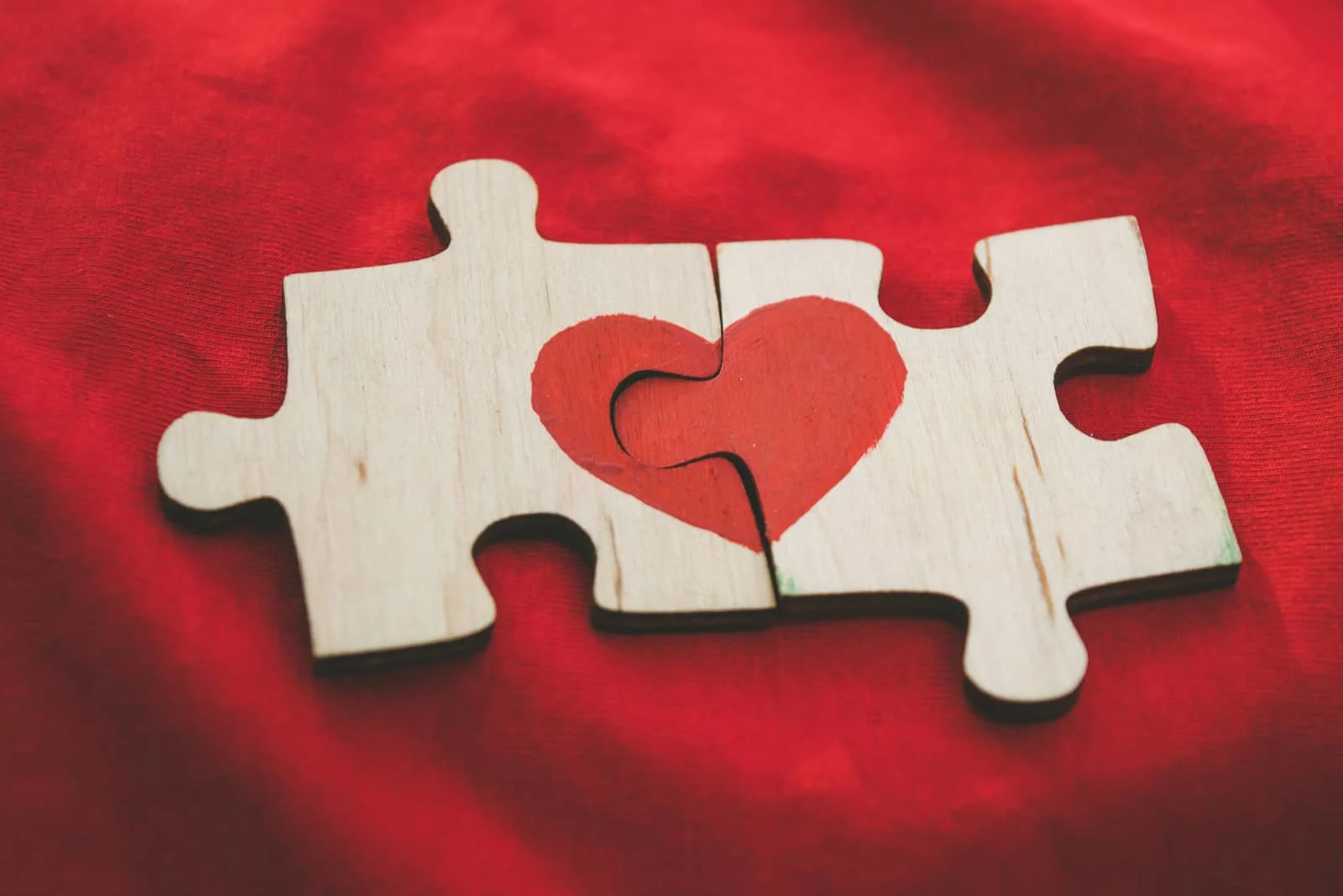 Auf die Teile des Holzpuzzles ist ein rotes Herz gezeichnet