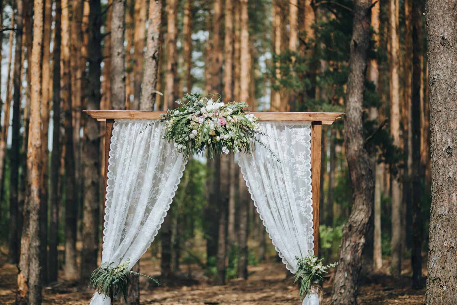 Bogen für die Hochzeitszeremonie, dekoriert mit Stoffblumen und viel Grün