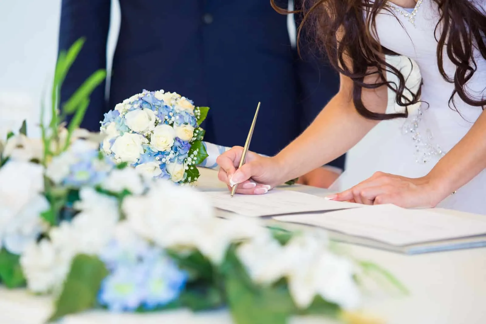 Brauthand mit einem Stift, der Hochzeitslizenz unterzeichnet (1)