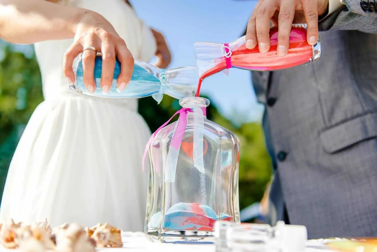 Bräutigam und Braut setzen Sand in Flasche