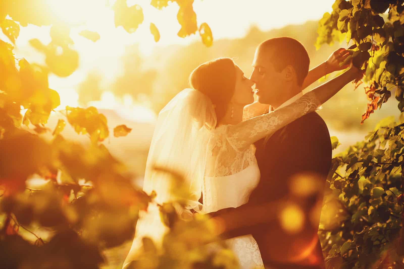 Das Brautpaar umarmt und küsst sich bei Sonnenuntergang