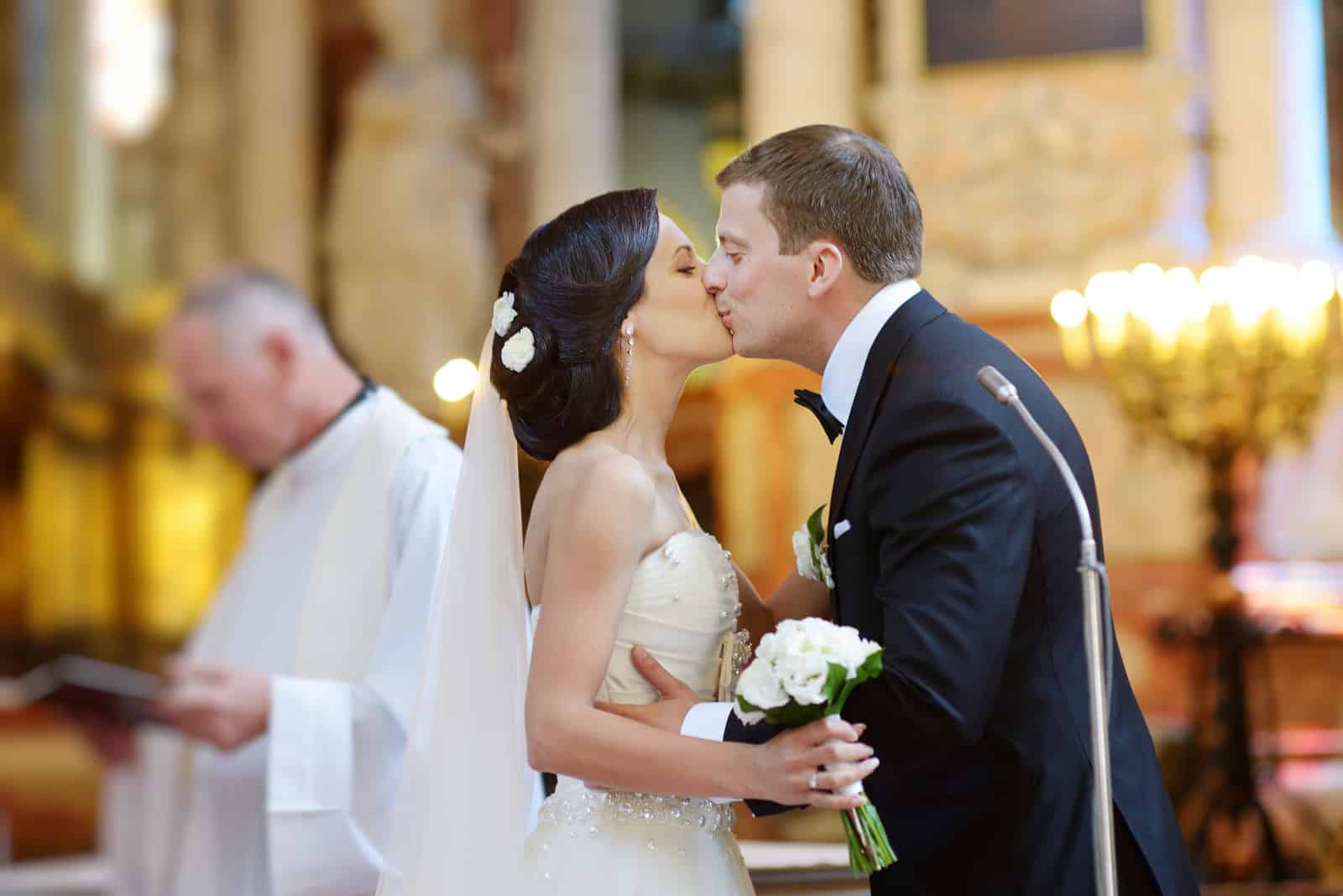Der Bräutigam küsst die Braut vor dem Altar