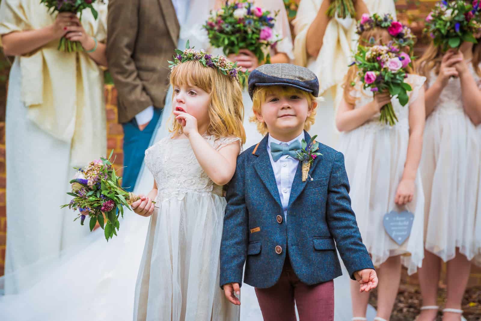 Die kleinen fröhlichen Kinder stehen zusammen bei der Hochzeit