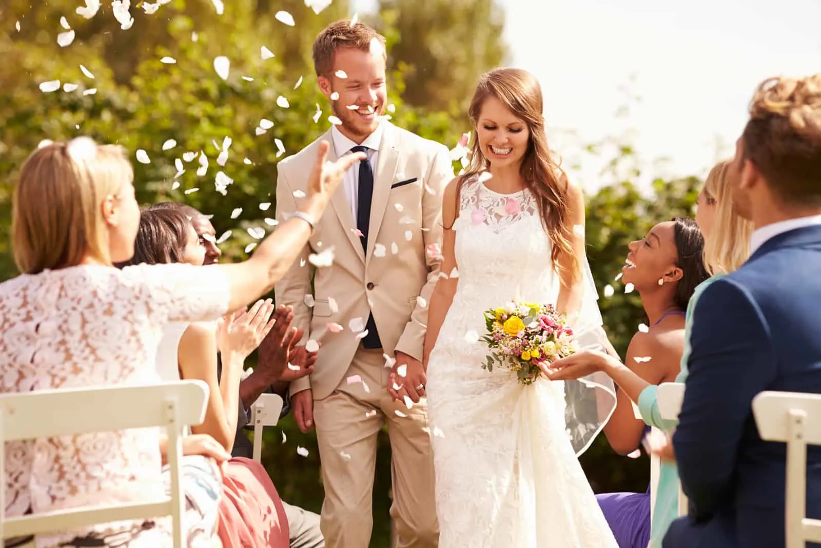 Gäste, die Konfetti über Braut und Bräutigam bei der Hochzeit werfen