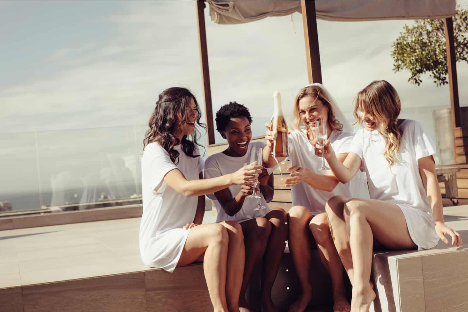 Glückliche junge Frauen, die Champagner am Junggesellenabschied auf dem Dach trinken