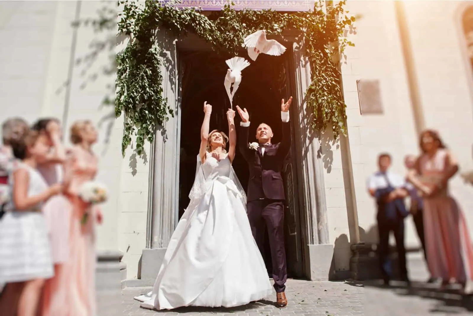 Hochzeitspaar mit freisetzenden Tauben in den Himmel gegen Kirchentor