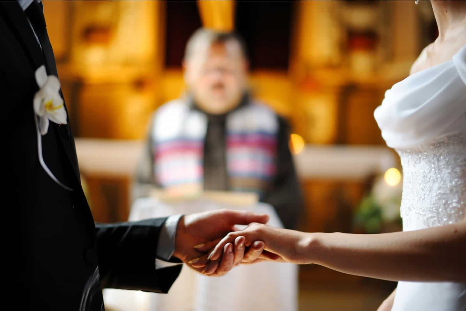 In der Kirche halten die Jungvermählten Hände vor dem Priester