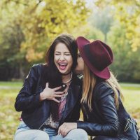 Zwei Mädchen in einem Park auf einer Bank lachen