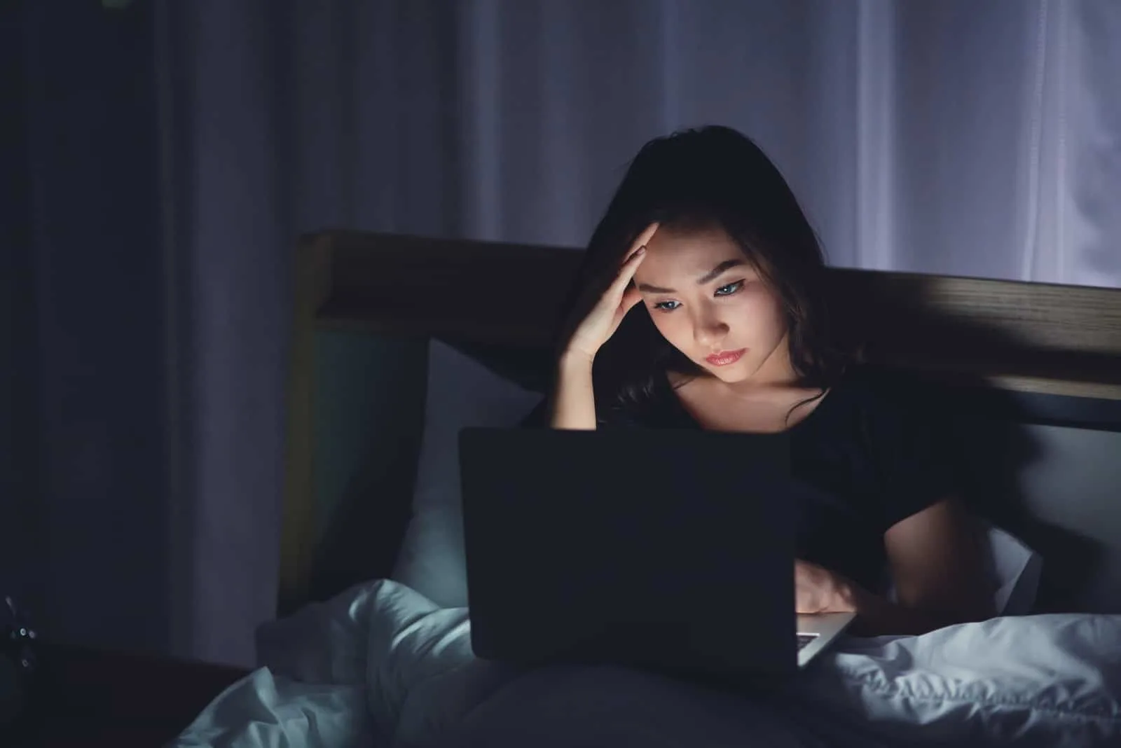 Abends im Bett benutzt eine Frau einen Laptop