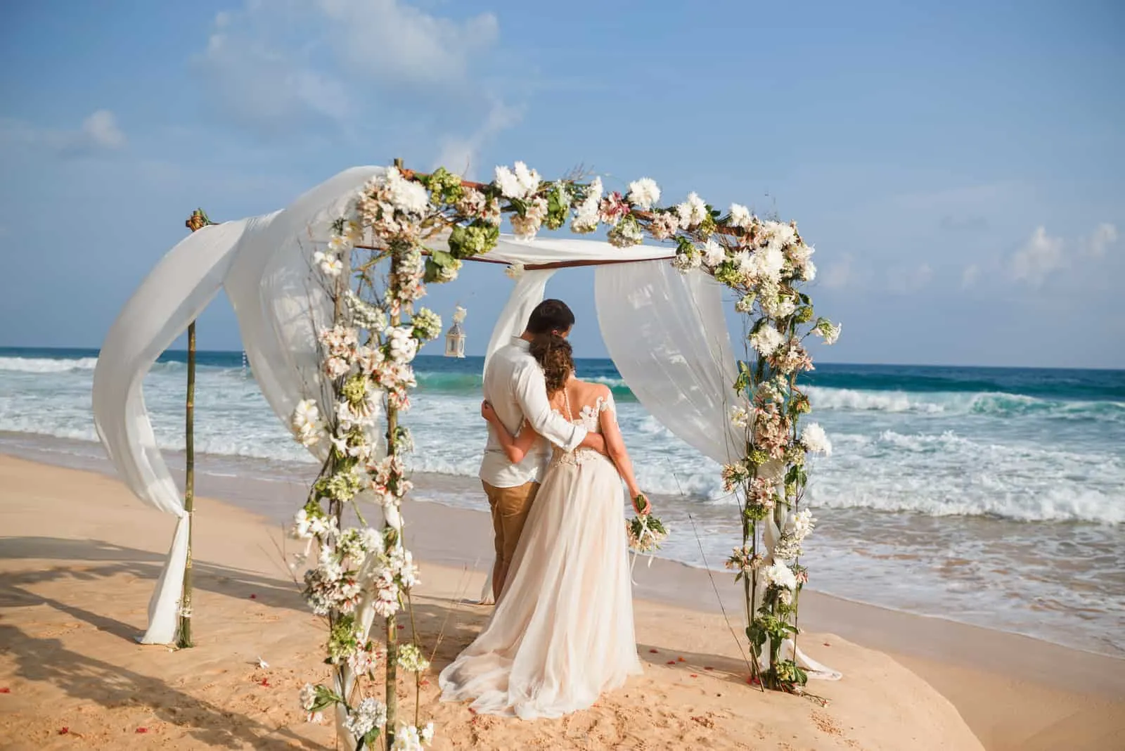 Braut und Bräutigam umarmen sich am Strand
