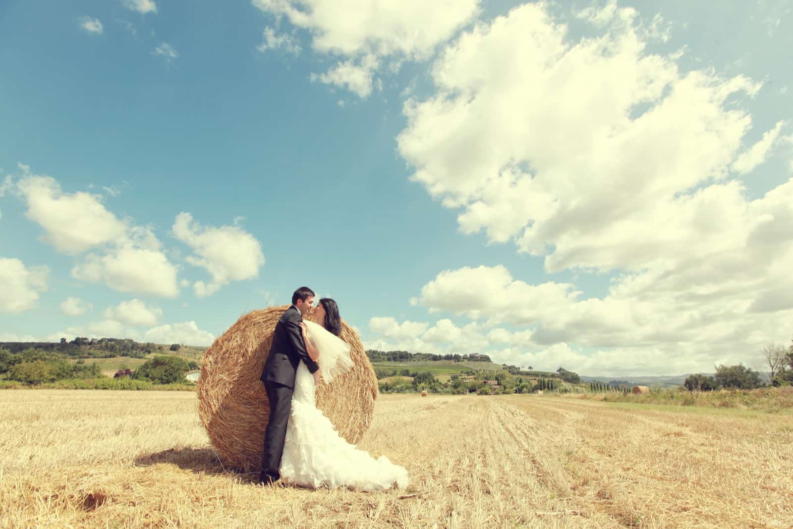 Braut und Bräutigam küssen in einem Weizenfeld