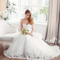 Braut im schönen Kleid sitzt auf dem Sofa