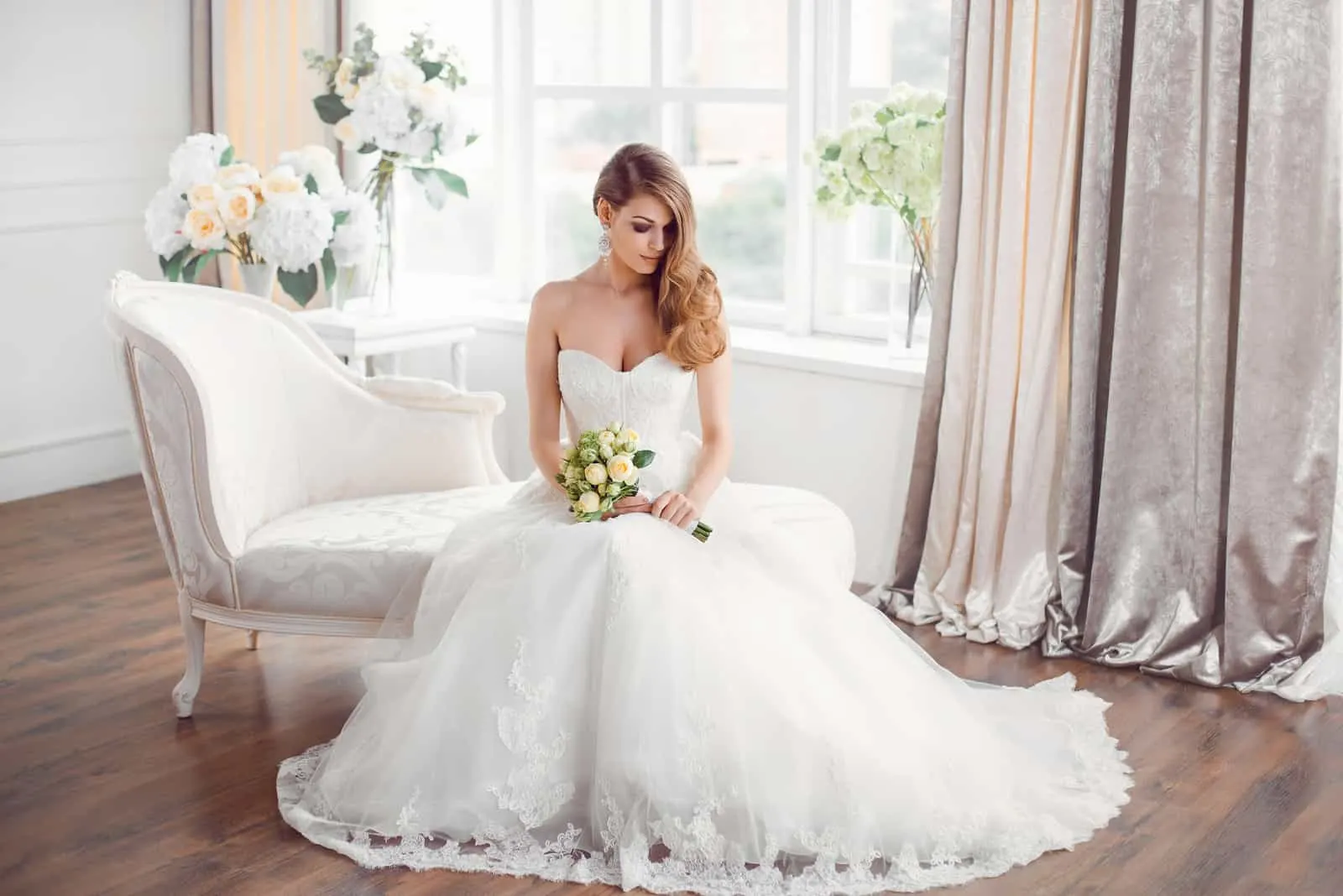 Bride in beautiful dress sitting on sofa