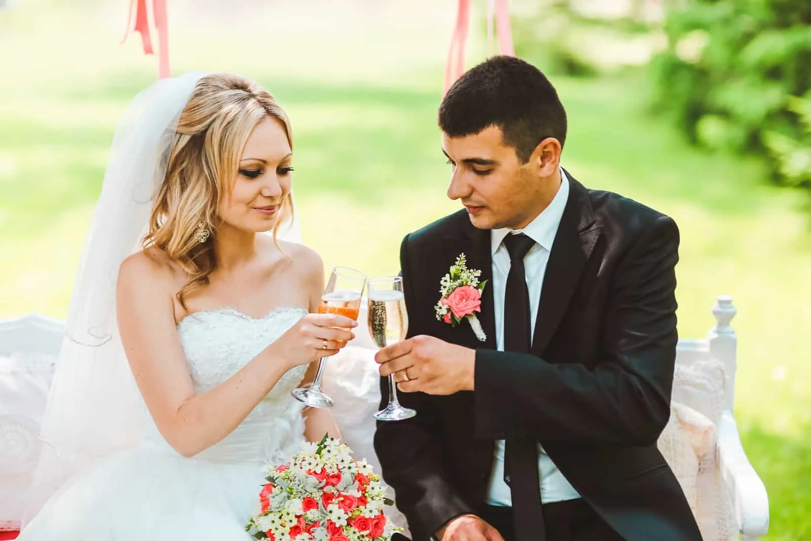 Das Brautpaar auf der Bank röstet mit Champagner