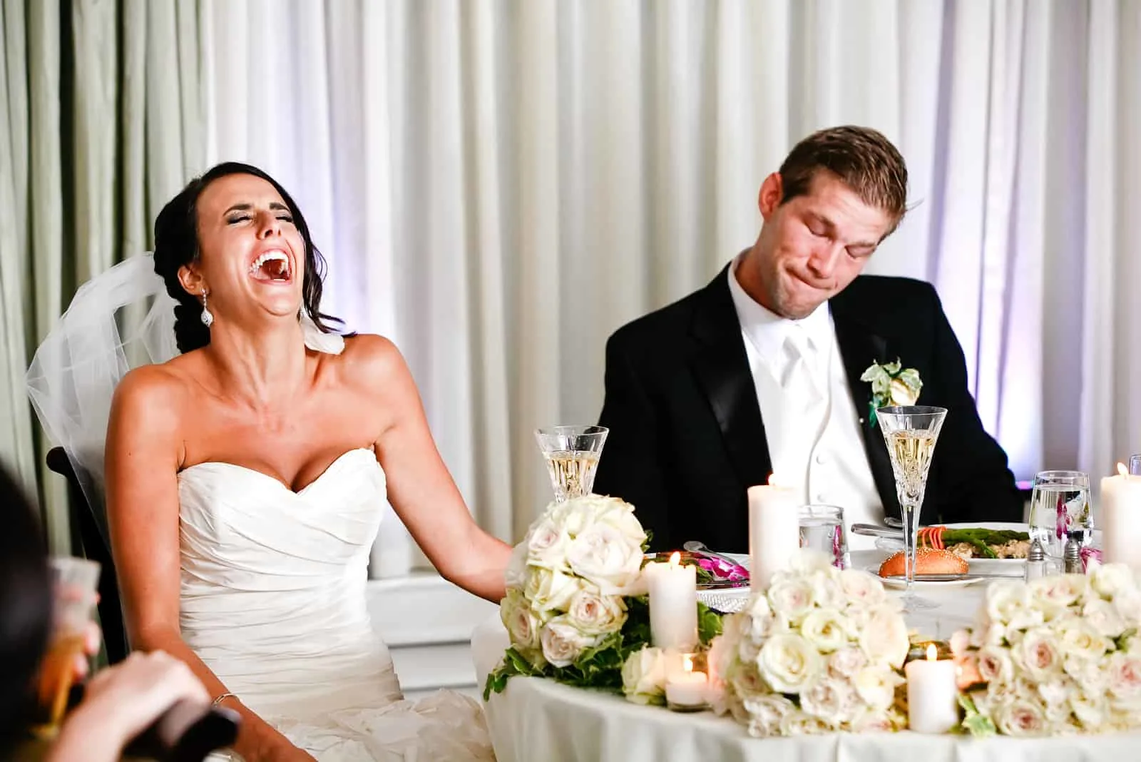 Das Brautpaar sitzt am Tisch und lacht
