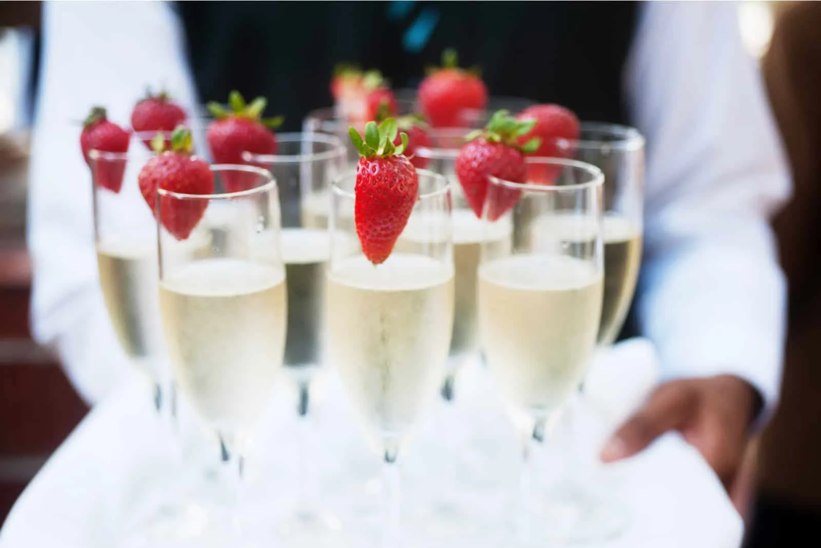 Der Kellner serviert Champagner mit Erdbeeren