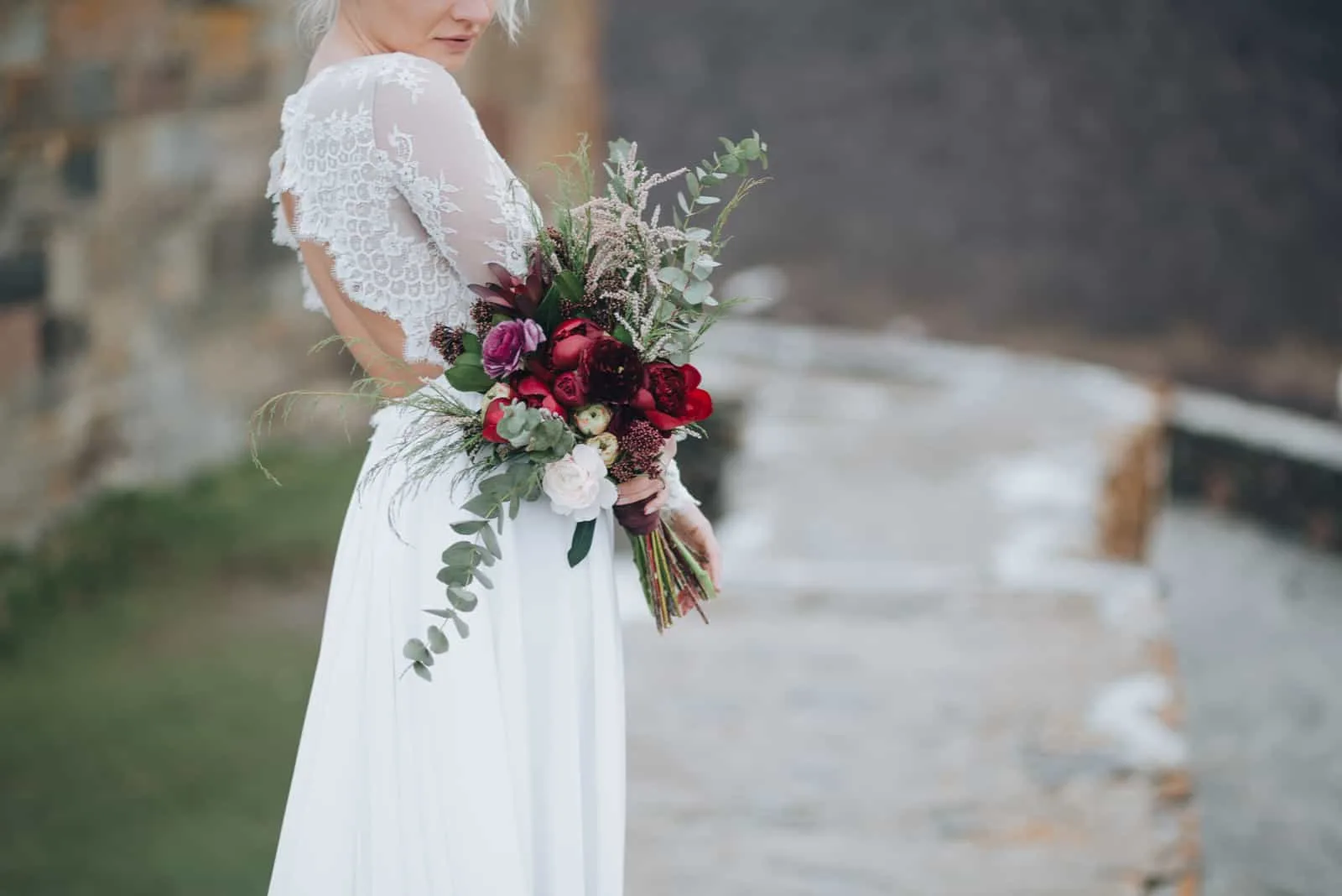 Die Braut mit einem Blumenstrauß in der Hand steht