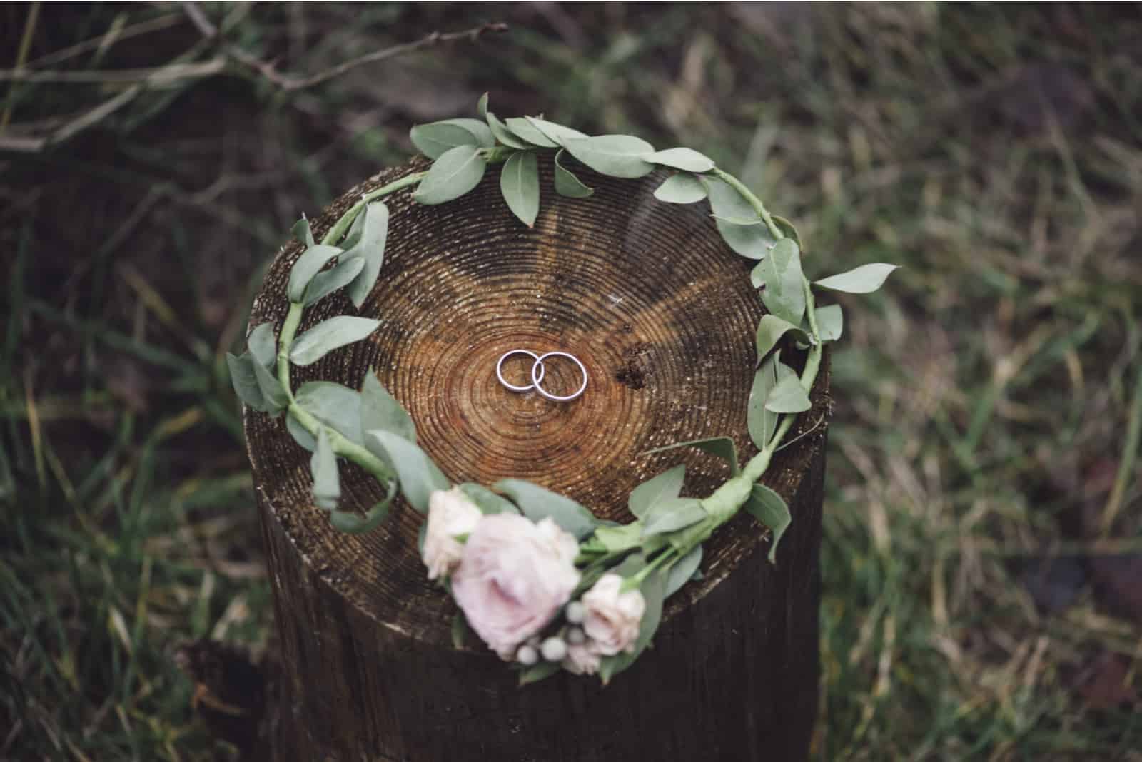 Eheringe in einem Blumenstirnband auf einem Holzstumpf