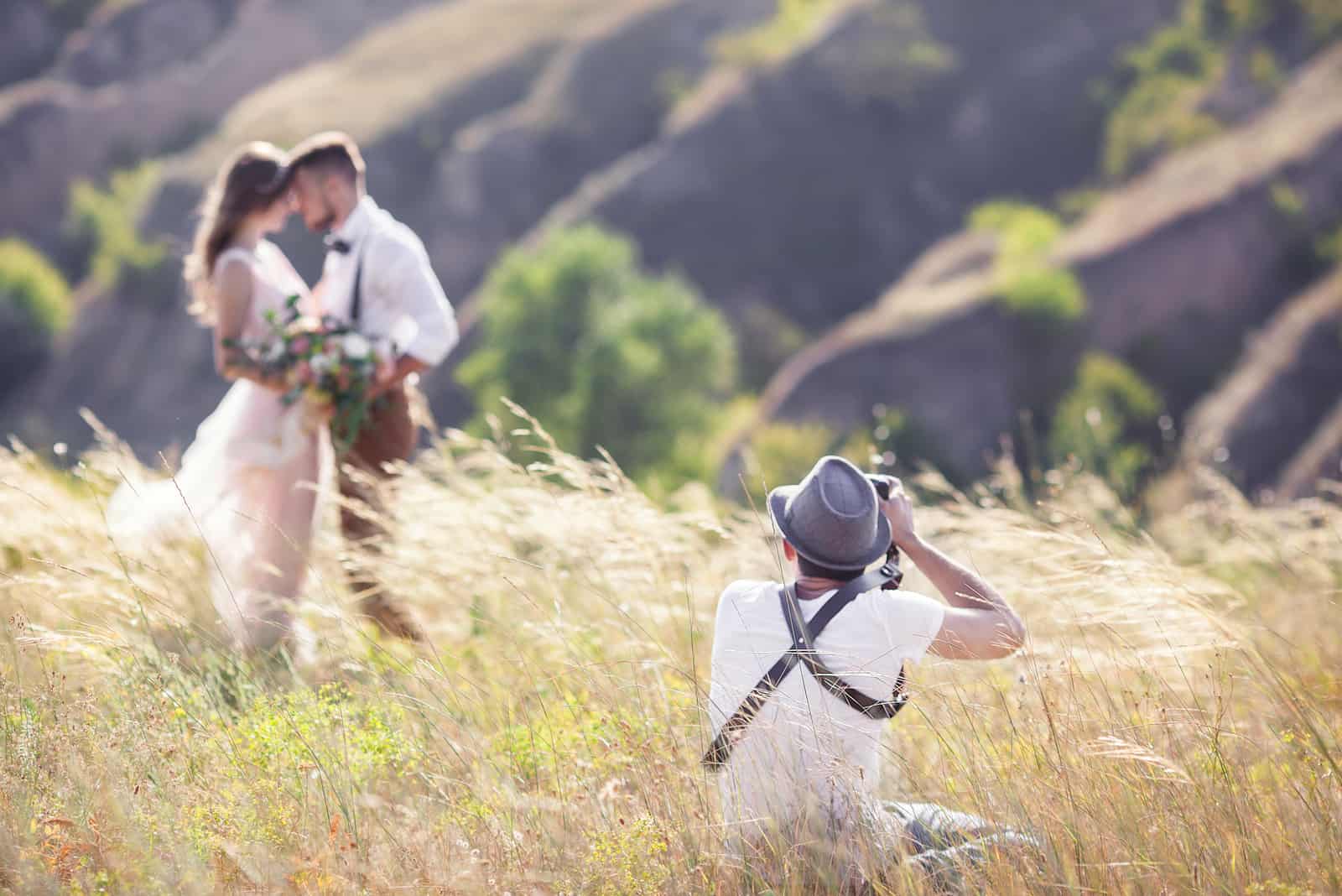 Ein Hochzeitsfotograf fotografiert Braut und Bräutigam in der Natur