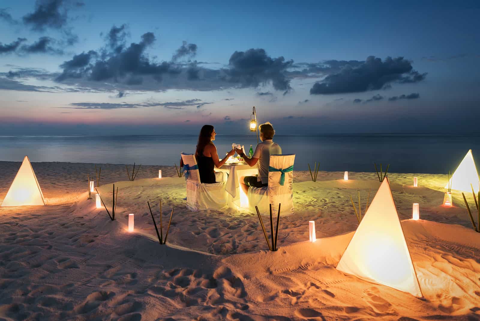 Flitterwochenpaar hat ein privates, romantisches Abendessen an einem tropischen Strand