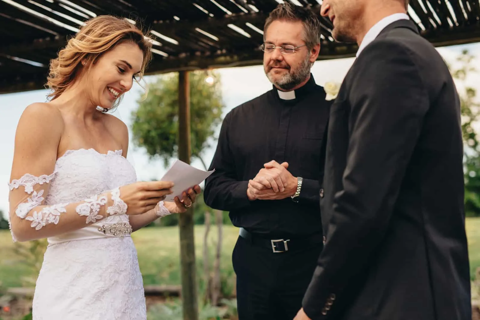 Frau las Gelübde vom Papier für ihren Ehemann am Hintergrund der Hochzeitszeremonie