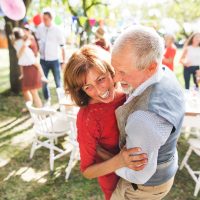 Ein älteres Paar tanzt auf einer Gartenparty draußen im Hinterhof