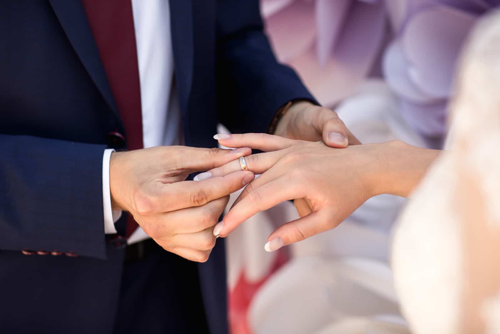 Hände von Braut und Bräutigam im feierlichen Prozess des Ringwechsels