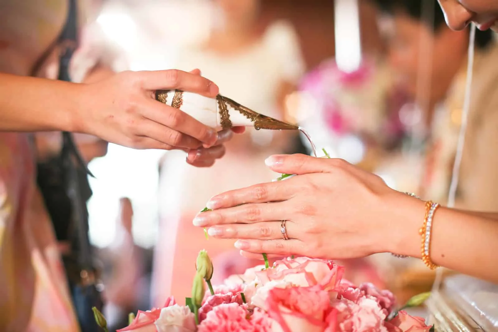 Hände, die Segenwasser in Brautbänder gießen, thailändische Hochzeit