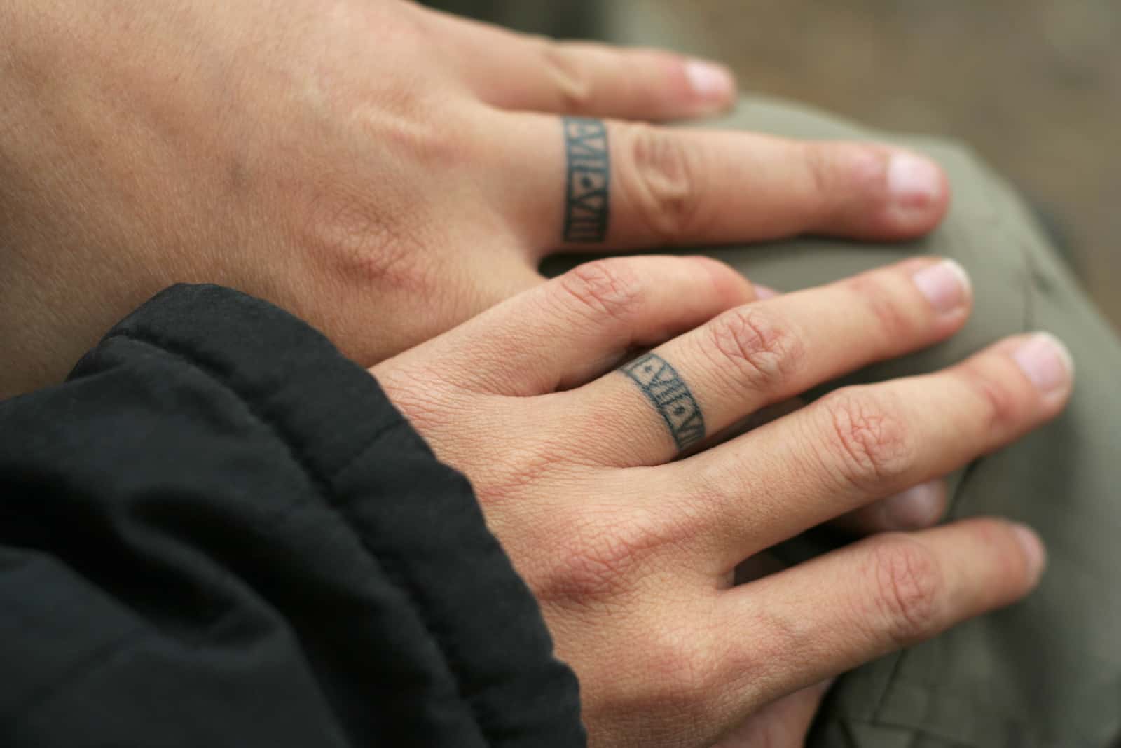 Hände eines Paares mit tätowierten Ringen