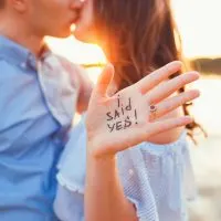 Vorschlag am Strand mit einem Mann, der darum bittet, seine glückliche Freundin zu heiraten