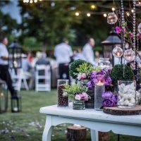 Hochzeitszeremonie mit Blumen draußen im Garten mit hängenden Lichtern