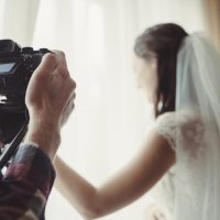 Der Kameramann nimmt die Braut auf, die aus dem Fenster schaut