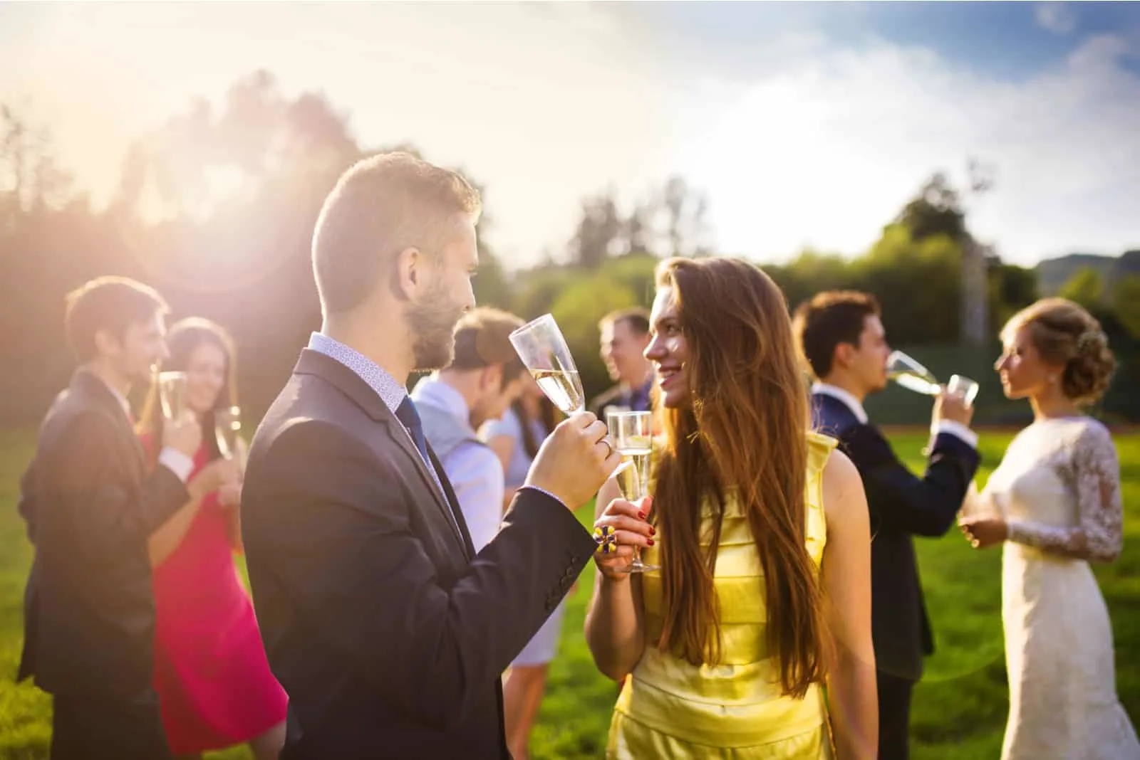 Hochzeitsgäste genießen Champagner bei Sonnenuntergang