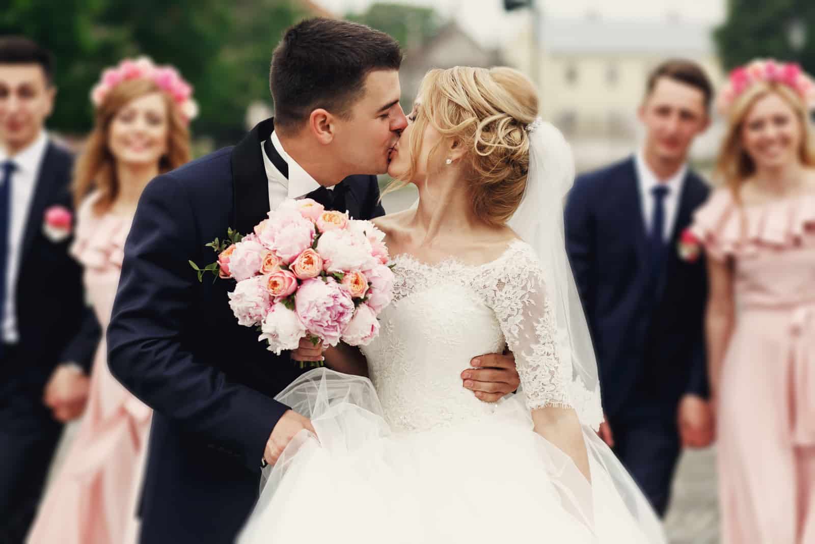 Hübscher Bräutigam, der schöne Braut küsst