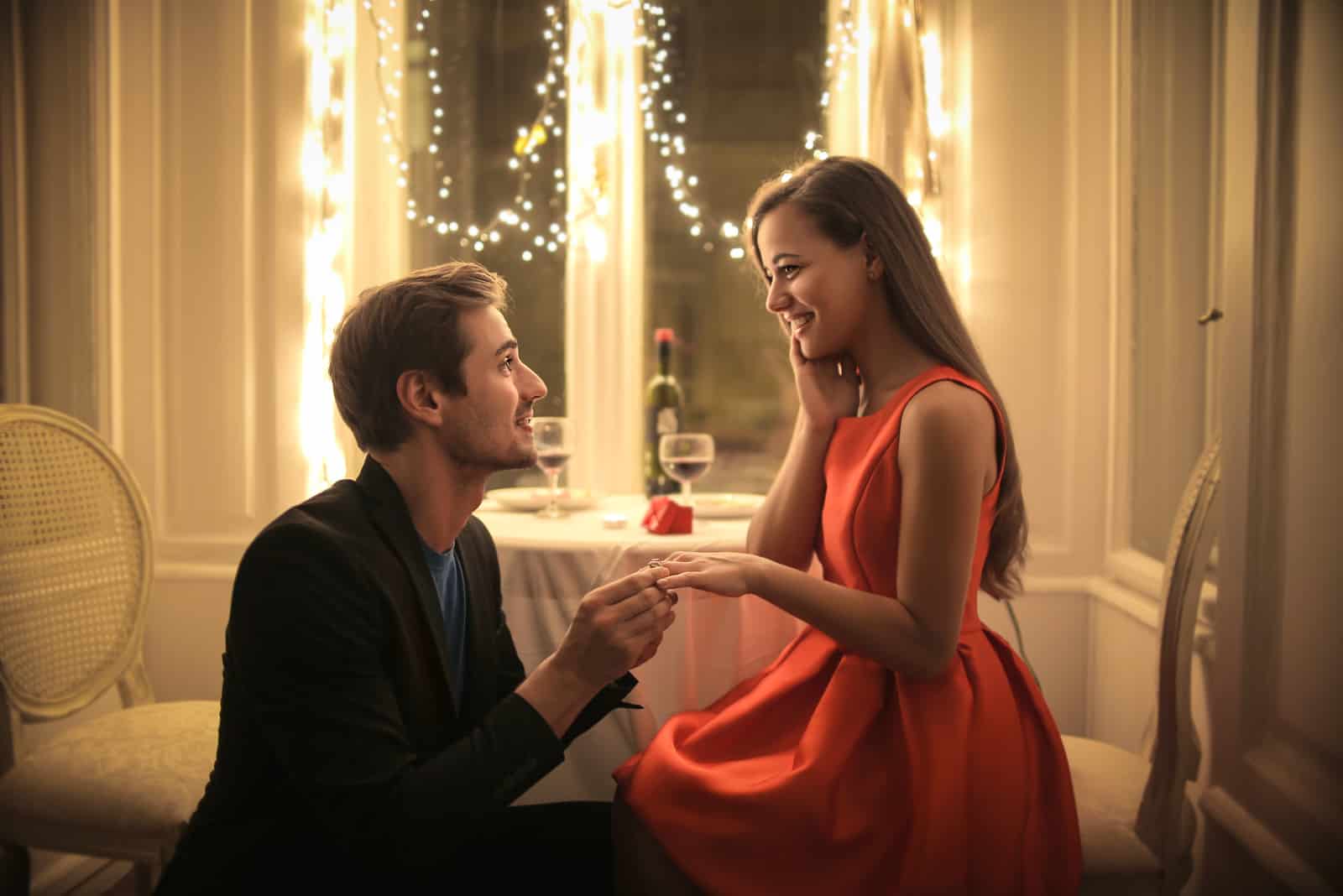 Hübscher Mann, der eine schöne Frau vorschlägt, um ihn in einem eleganten Restaurant zu heiraten