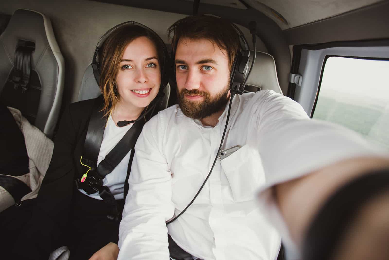Schönes Paar, das selfie in einem Hubschrauber nimmt, während es über die Stadt fliegt.