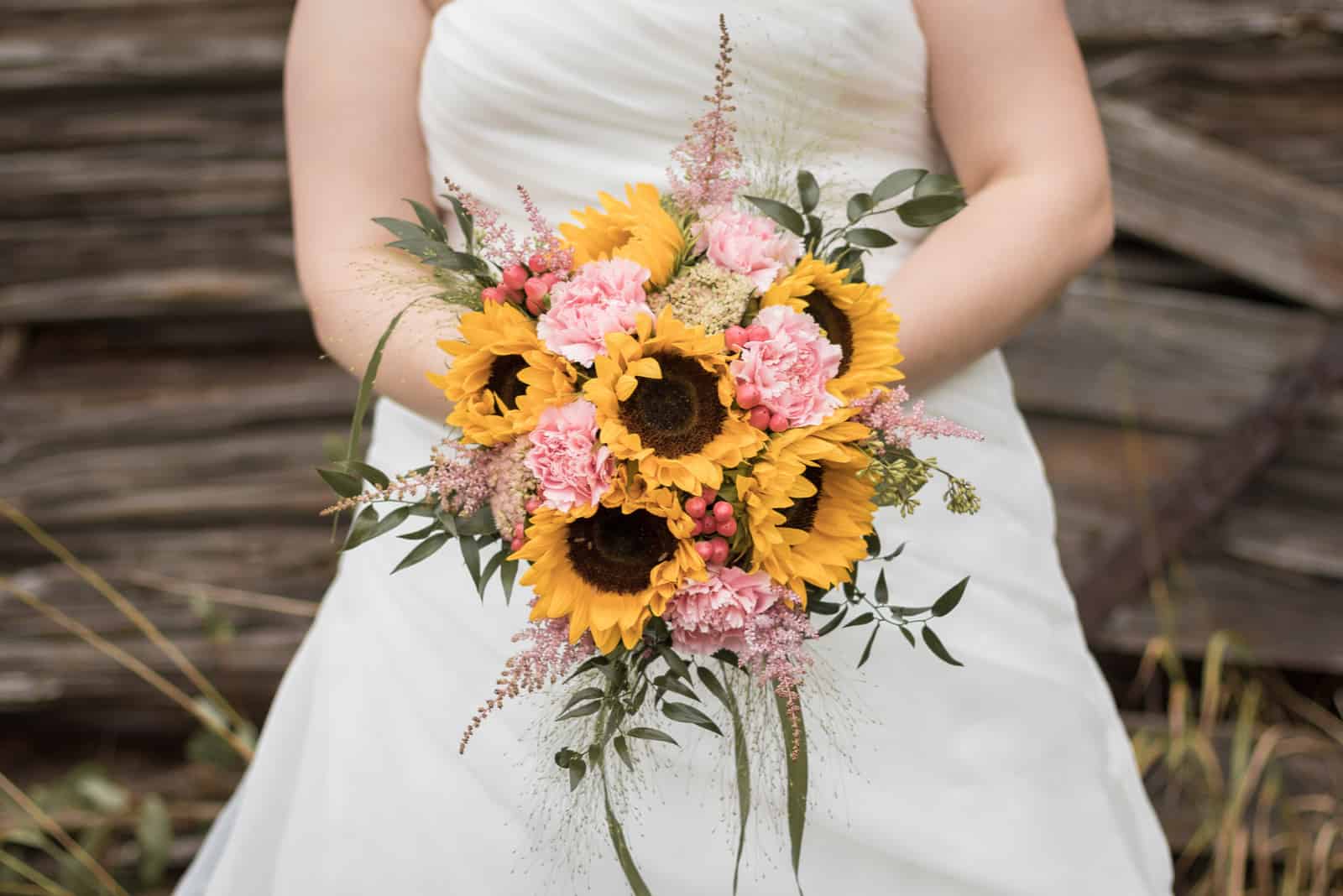 Sonnenblumenhochzeitsstrauß in den Händen der Braut