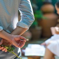 Mann, der wei&szlig;e Rose mit Ehering h&auml;lt, der Heiratsantrag macht