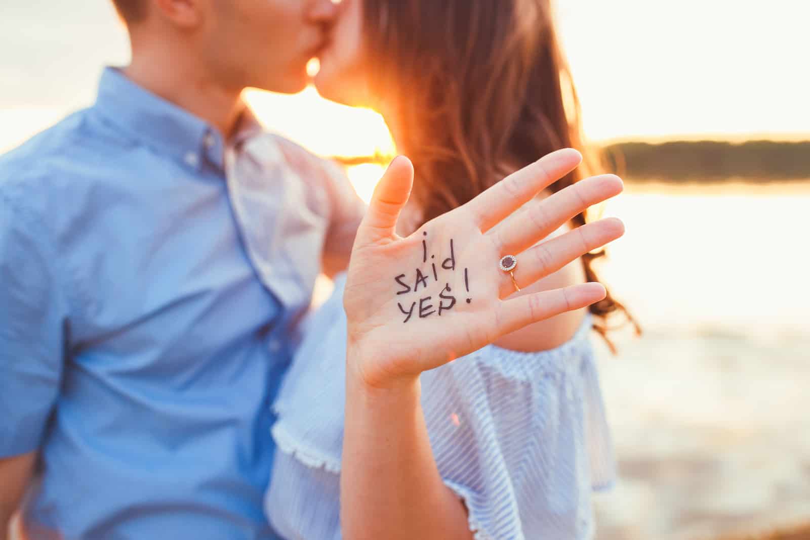 Vorschlag am Strand mit einem Mann, der darum bittet, seine glückliche Freundin zu heiraten