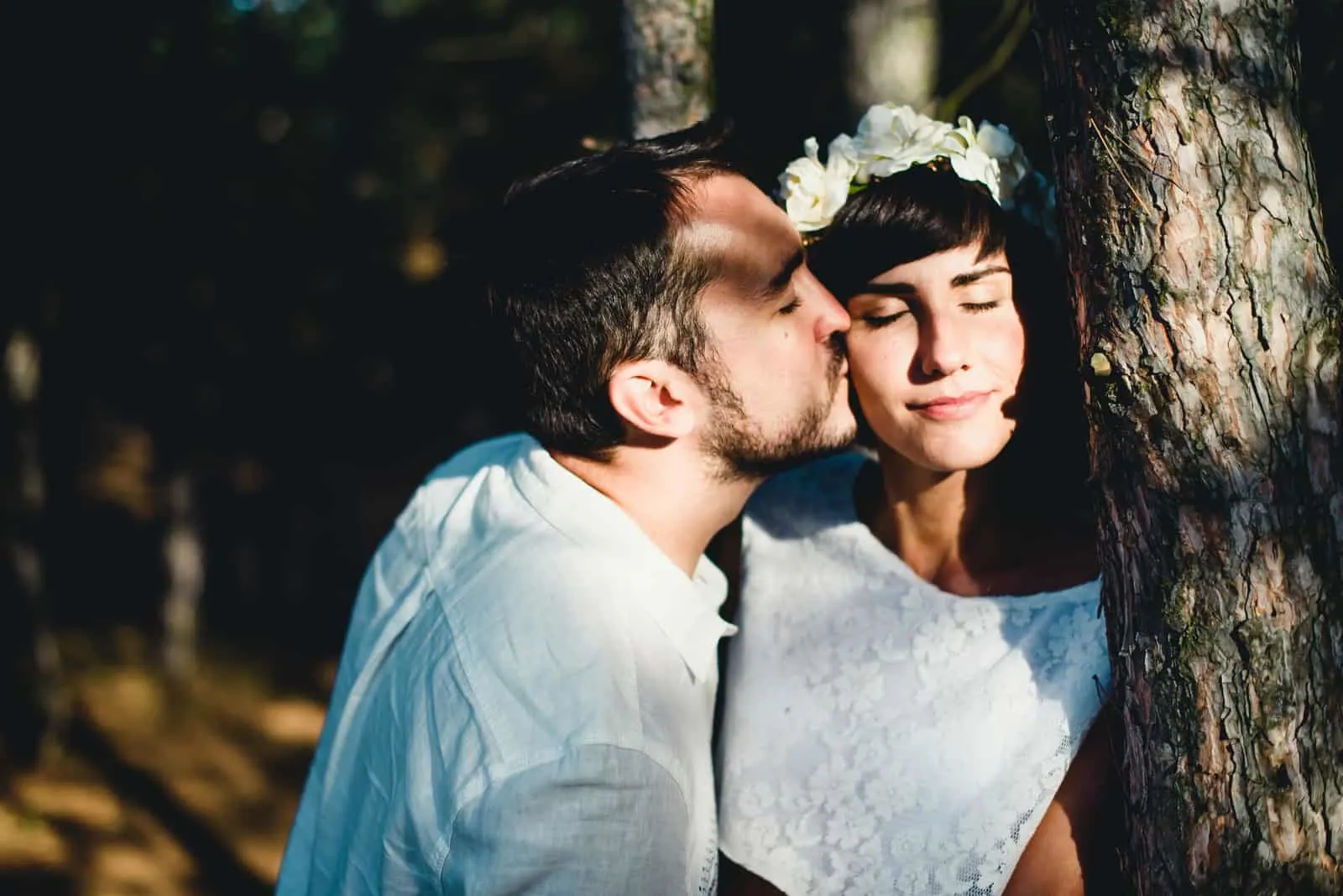 ein Hochzeitspaar küsst sich im Wald