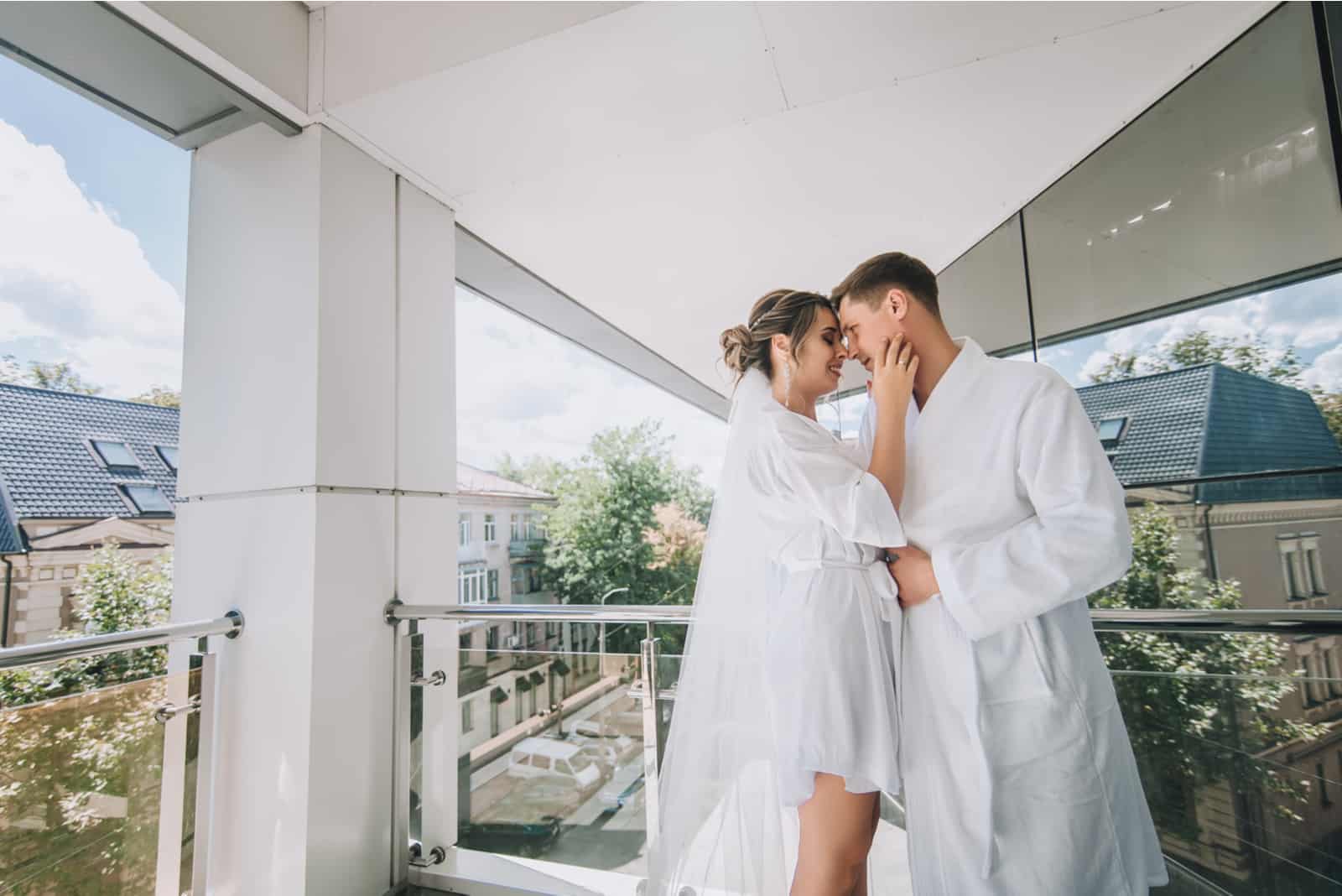 Am Morgen nach der Hochzeit küssen und umarmen sich die Jungvermählten leidenschaftlich auf der Terrasse
