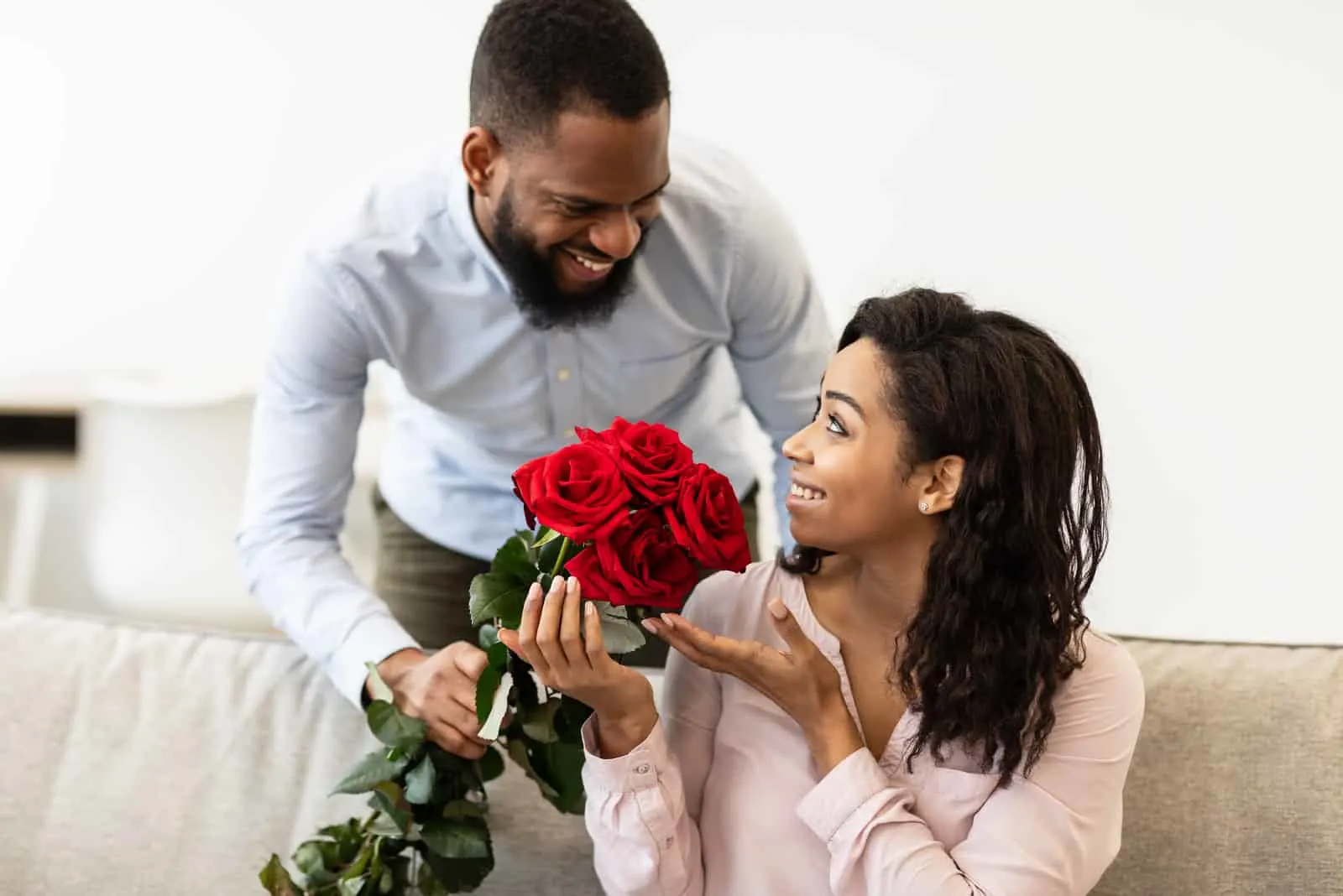 Der Ehemann gibt der glücklichen Frau einen Strauß roter Rosen
