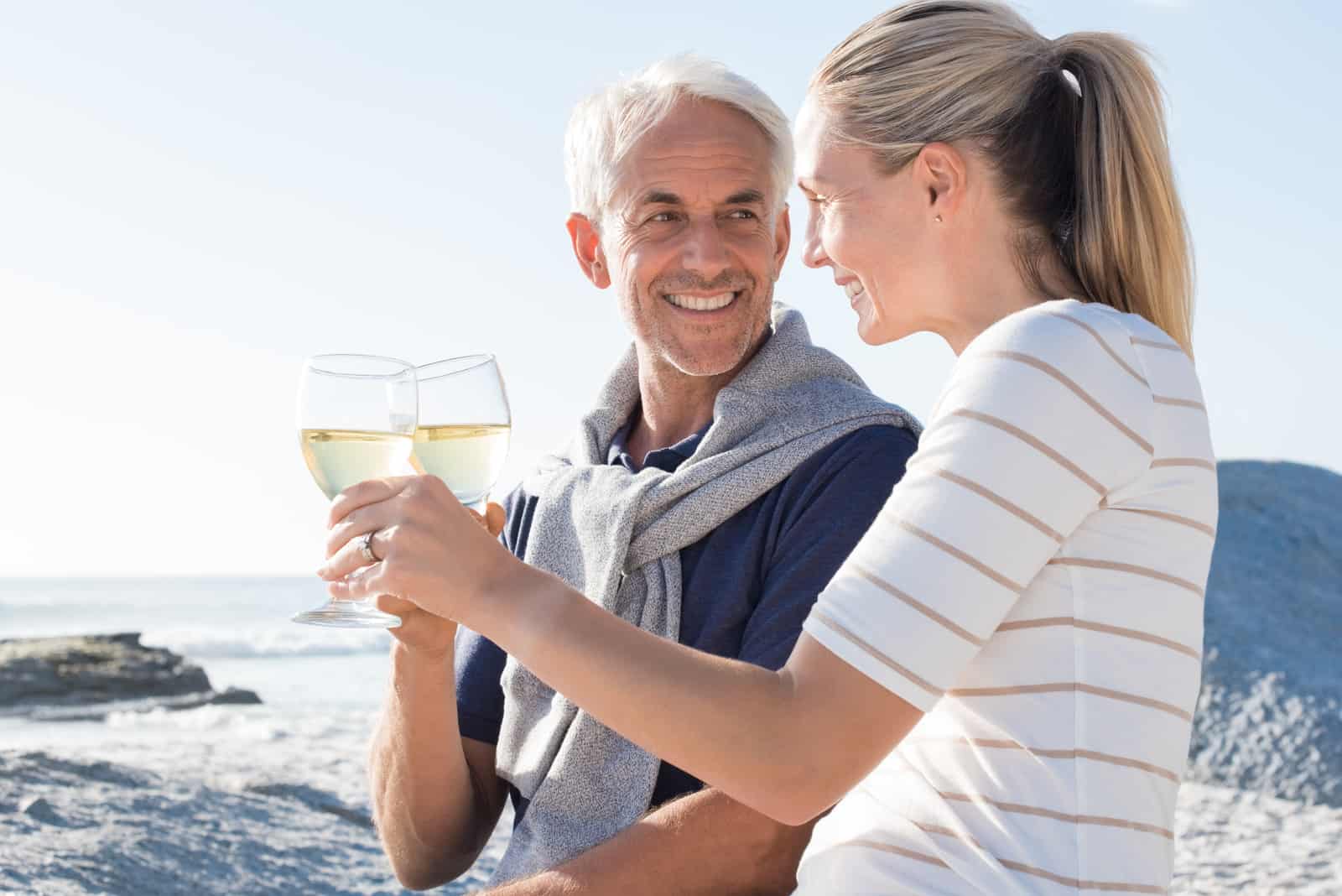 Ein älteres Ehepaar am Strand trinkt Wein