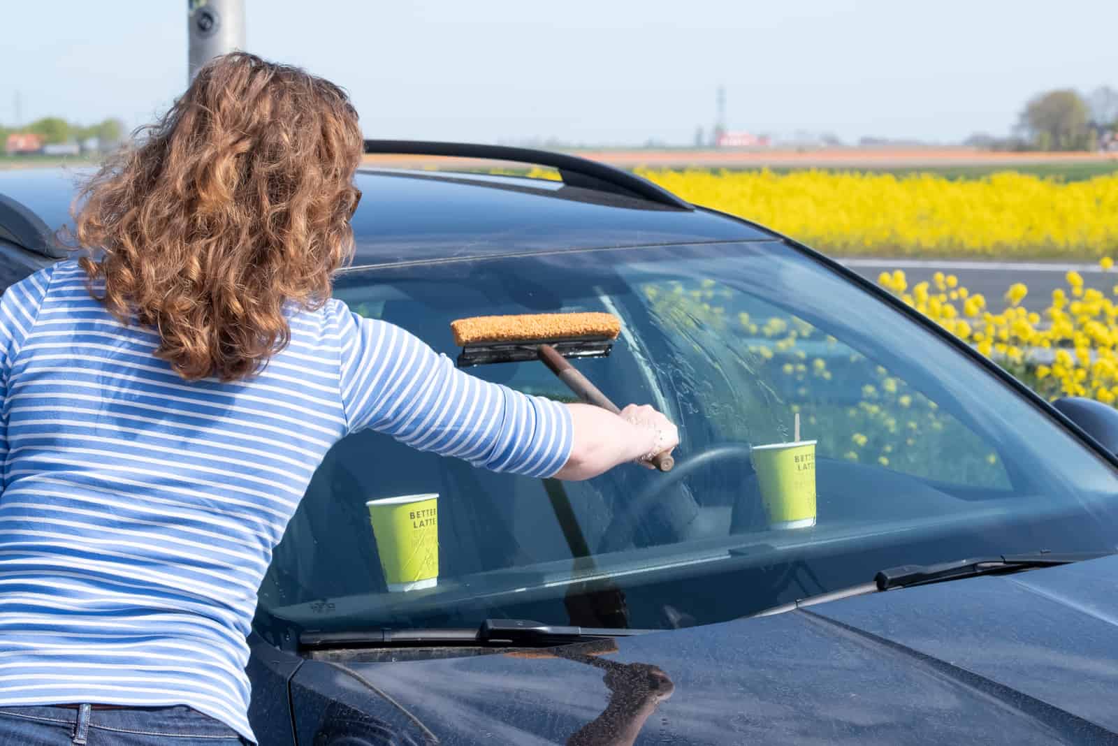 Eine Frau reinigt die Windschutzscheibe eines Autos